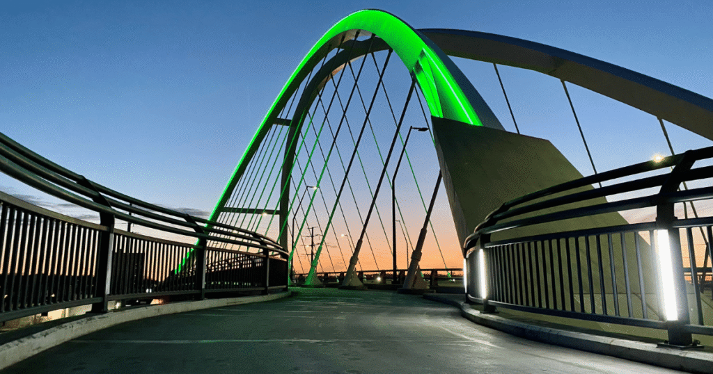 Lowry Bridge in Northeast Minneapolis at sunset with green lights, located in a vibrant and LGBTQ-friendly neighborhood