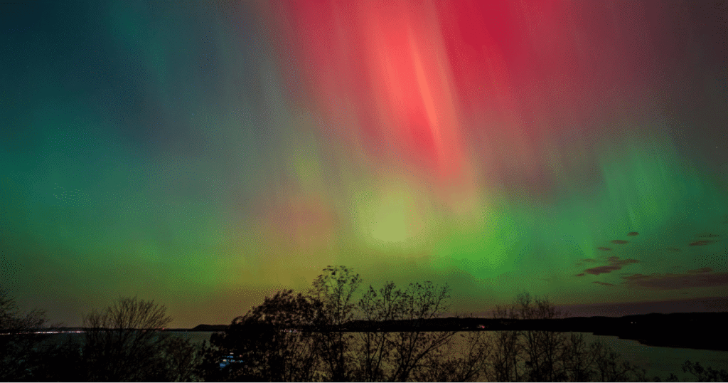 Northern lights visible from Minnesota with vibrant red and green aurora over a lake at night