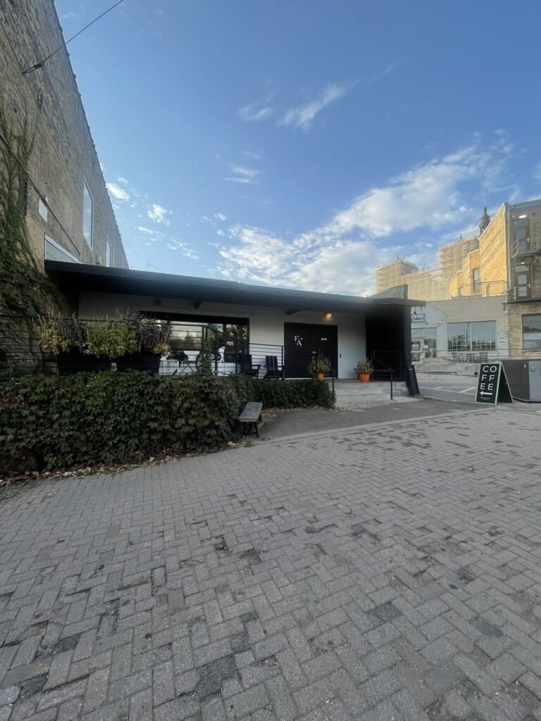 Low black and white building with the FA monogram and a COFFEE sandwich board in Fawkes Alley